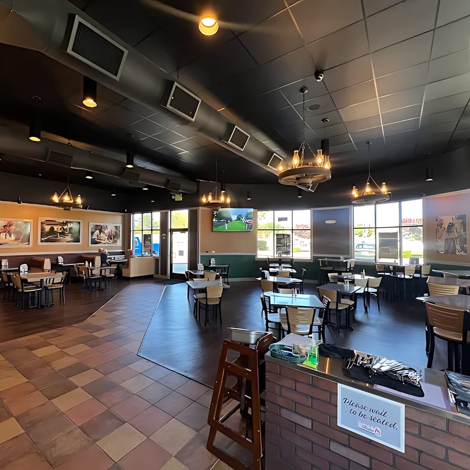 Spacious interior of Taqueria La Flama with tables, booths, a TV, and large windows.