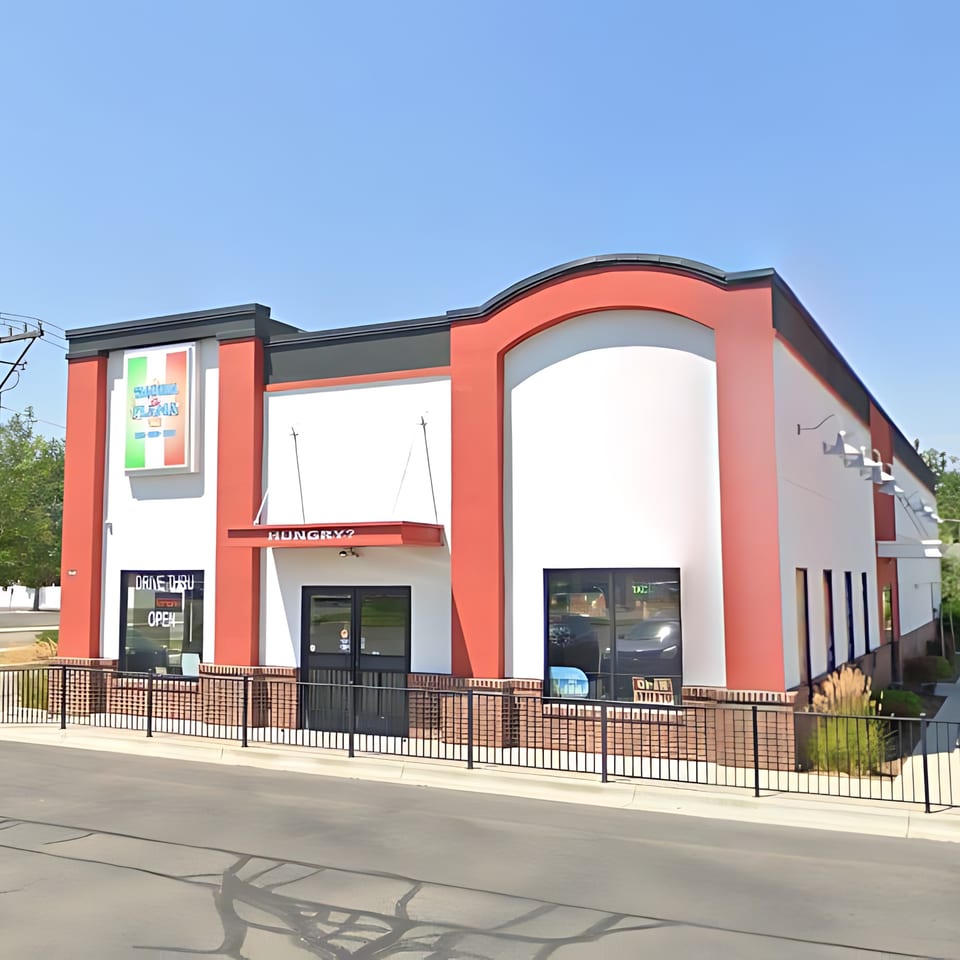 Exterior of Taqueria La Flama, a red and white building with a drive-thru and "Hungry?" sign.