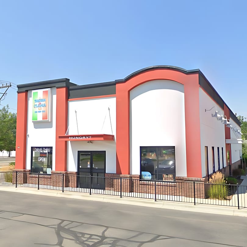 Exterior of Taqueria La Flama, a red and white building with a drive-thru and "Hungry?" sign.